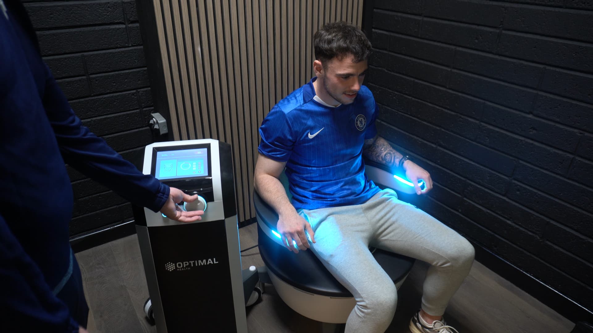 A client seated fully clothed on the HIFEM chair