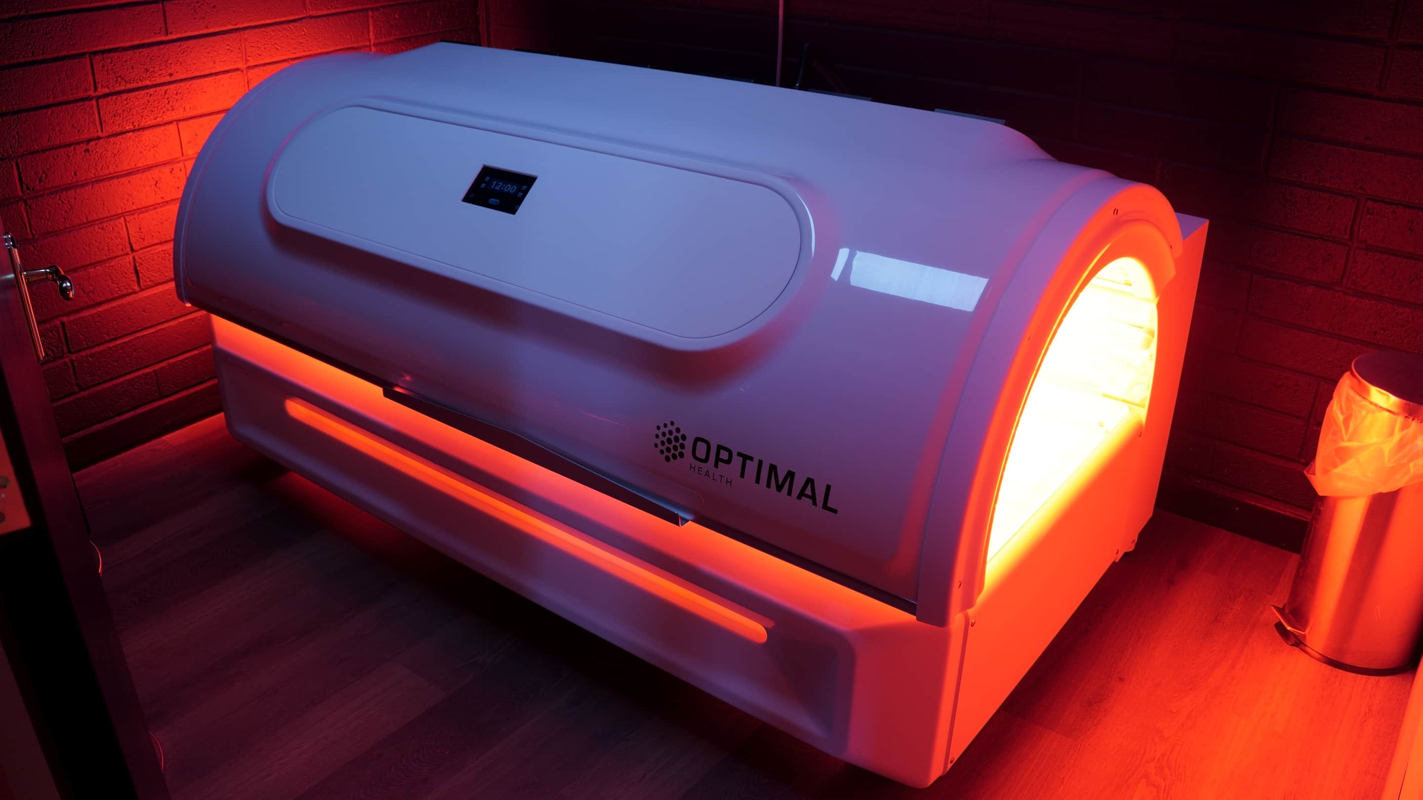 The infrared bed running, its red light spilling onto the brick wall behind it